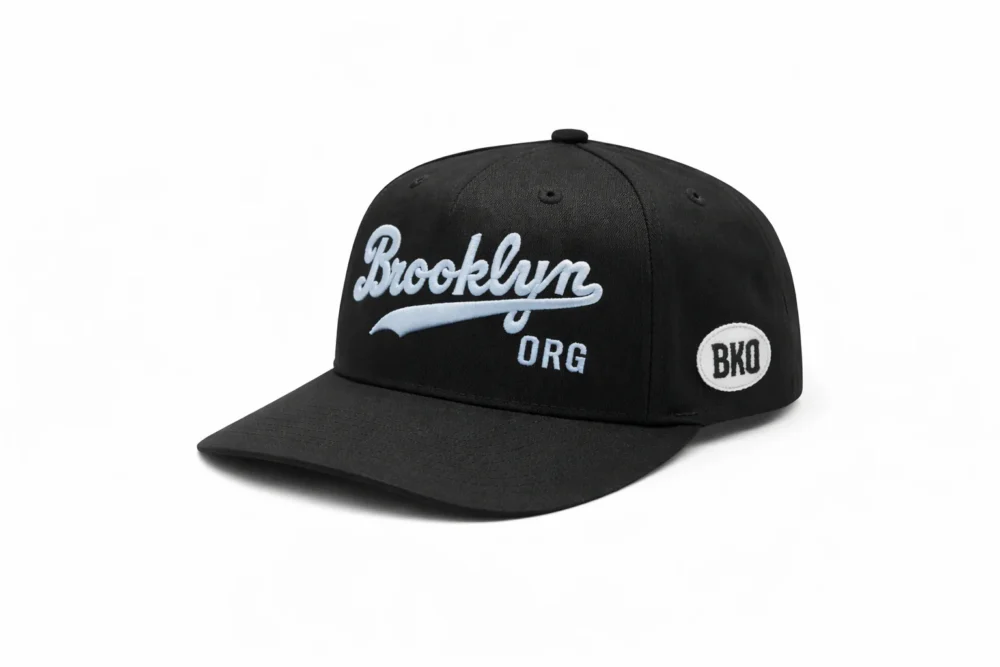 Black baseball cap with "Brooklyn ORG" embroidered in white on the front and a small white oval patch with "BKO" on the side.