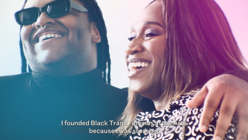 Two people smiling together, one wearing sunglasses and a black top, the other with long hair and a patterned outfit. Text reads: "I founded Black Trans Femmes in the Arts because I was studying.