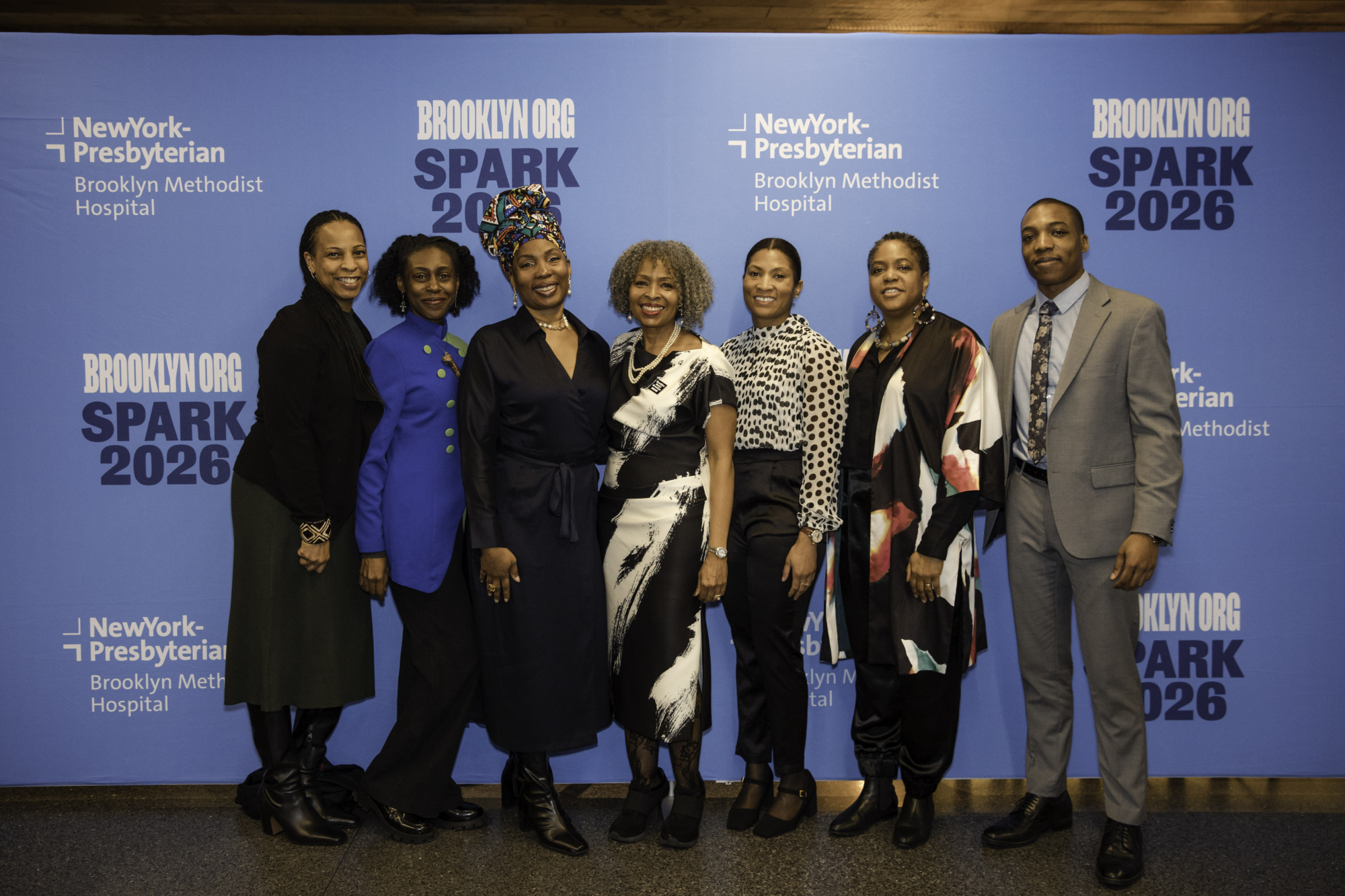 Seven people stand side by side, smiling in front of a blue backdrop with "NewYork-Presbyterian," "Brooklyn Methodist Hospital," and "SPARK 2026" logos.