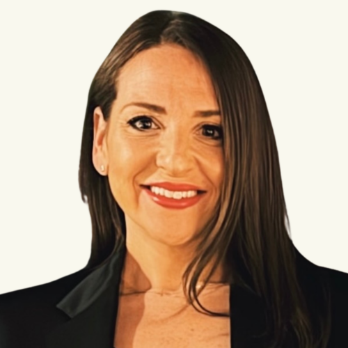 Woman with long brown hair, wearing a black blazer, smiling at the camera against a plain white background.