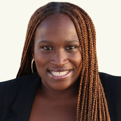 A woman with long, brown braided hair, wearing hoop earrings and a black jacket, smiles at the camera against a plain background.
