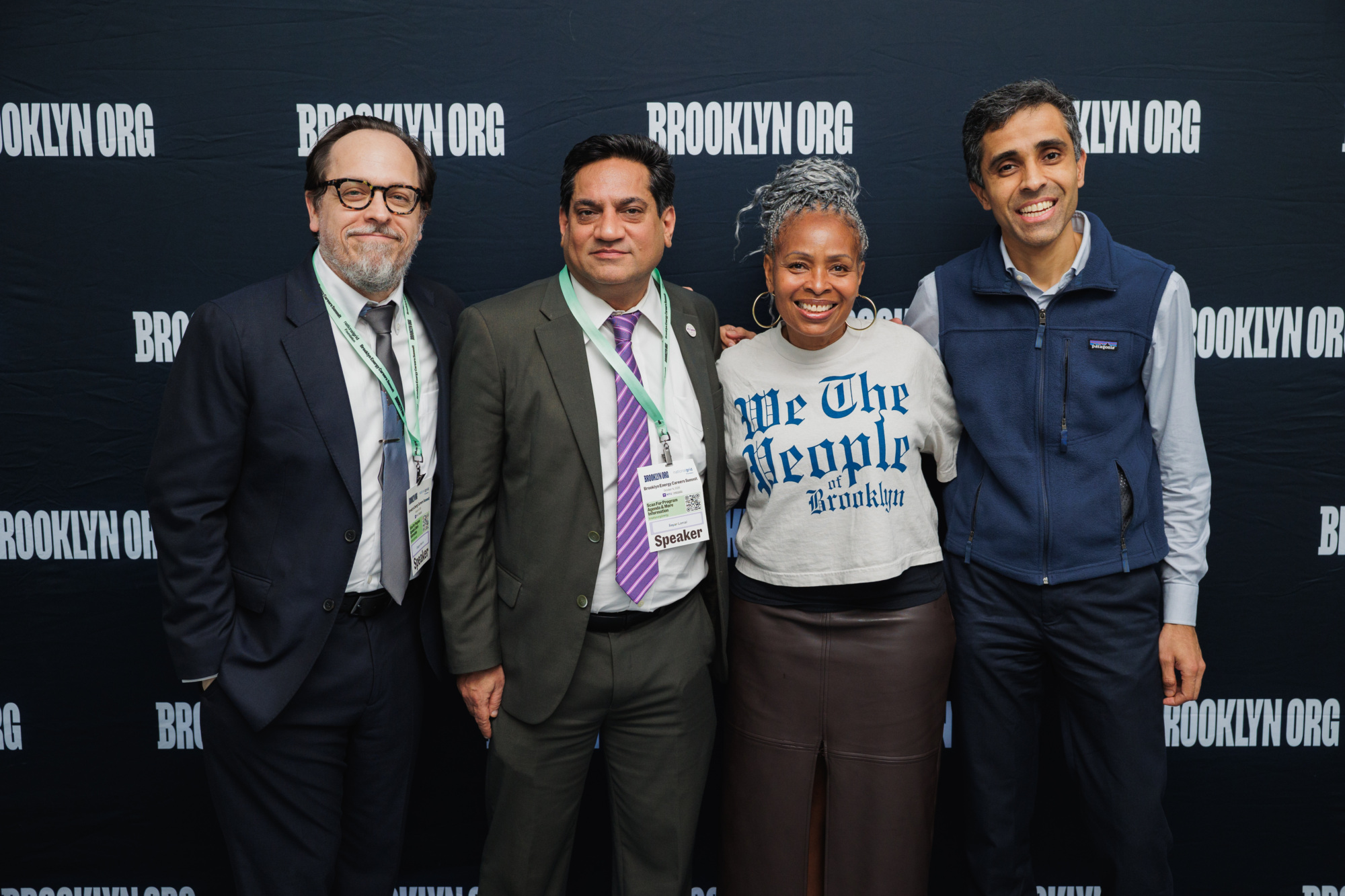 Four people standing in front of a backdrop featuring the Brooklyn.org logo.