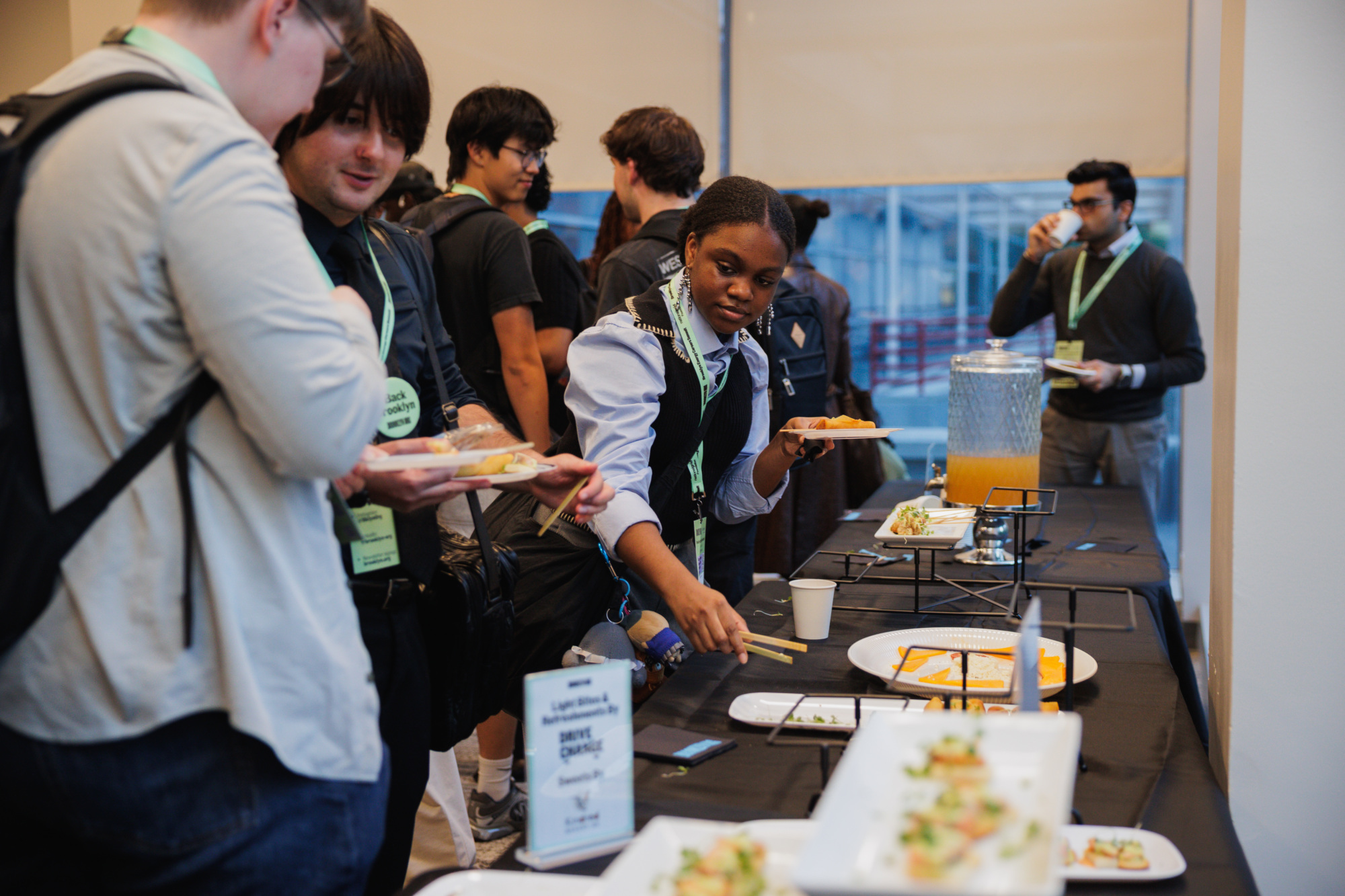People at a buffet table picking up food items on small plates.