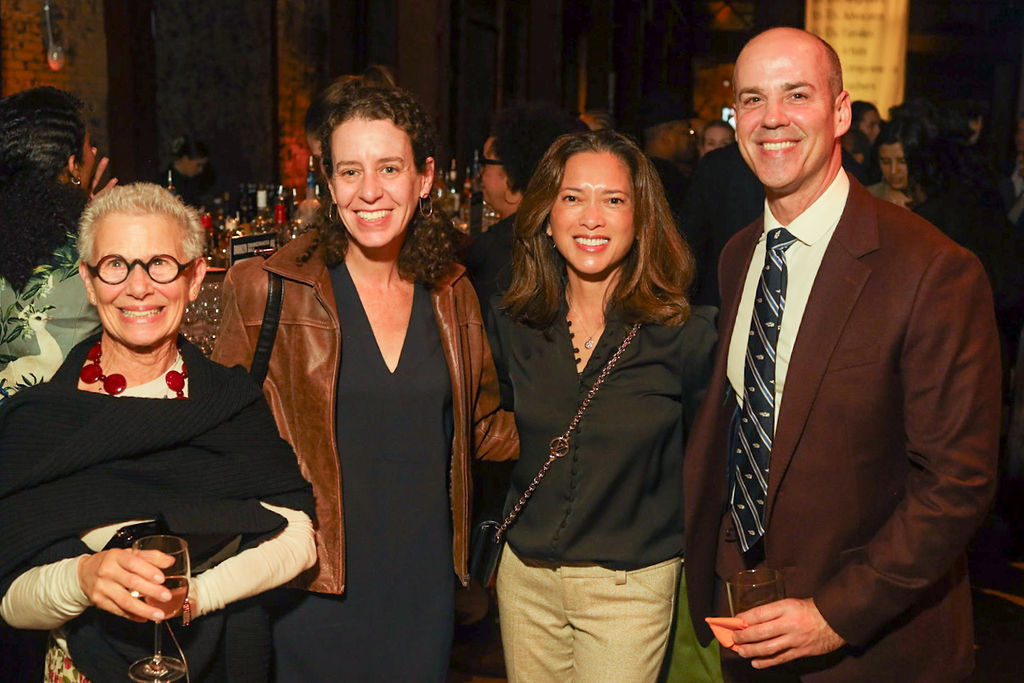 Four people smiling at a social gathering.