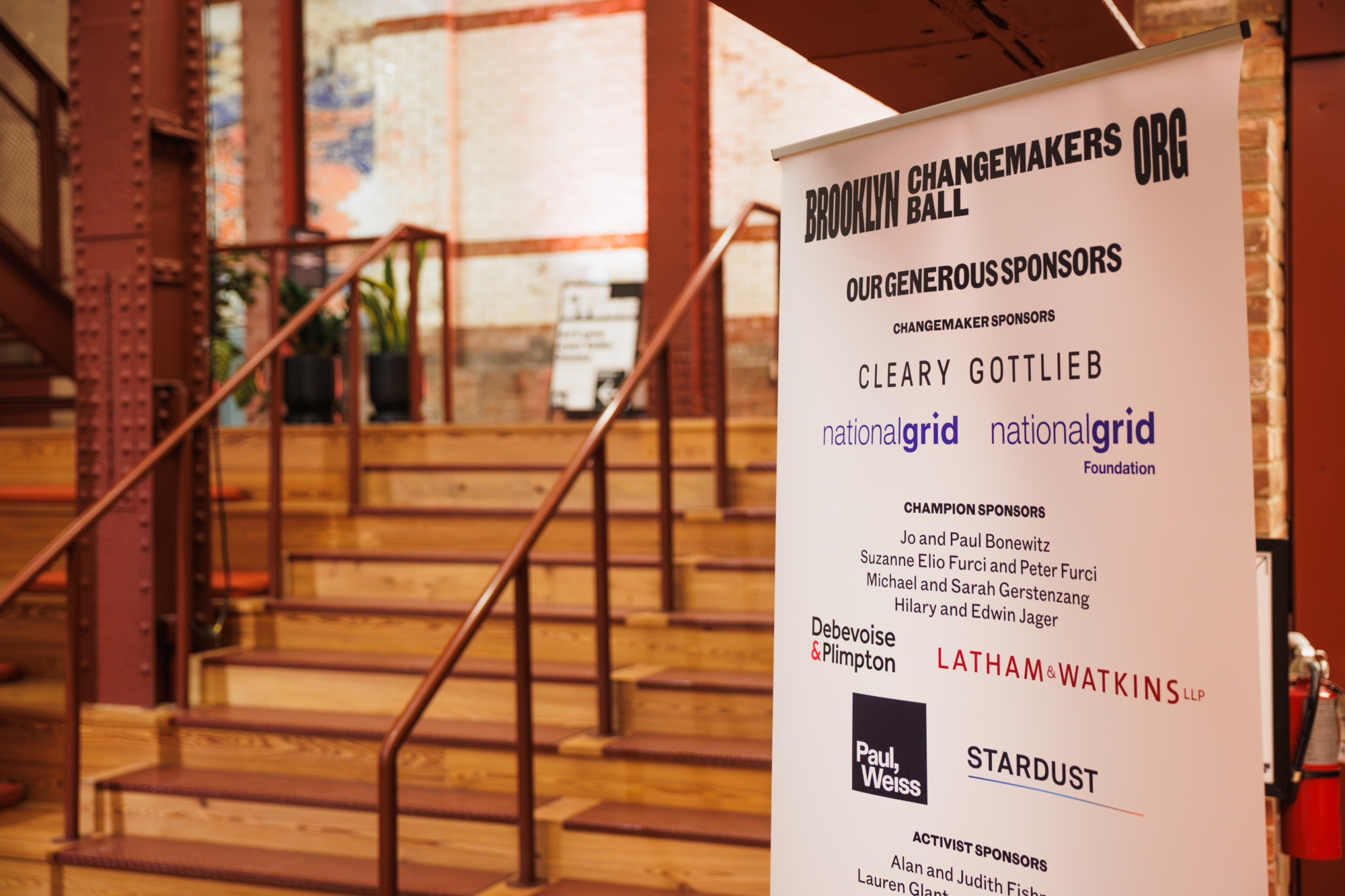 A vertical banner for the Brooklyn Changemakers Ball listing event sponsors, including Cleary Gottlieb, National Grid, Debevoise & Plimpton, Latham & Watkins, Paul, Weiss, and Stardust.