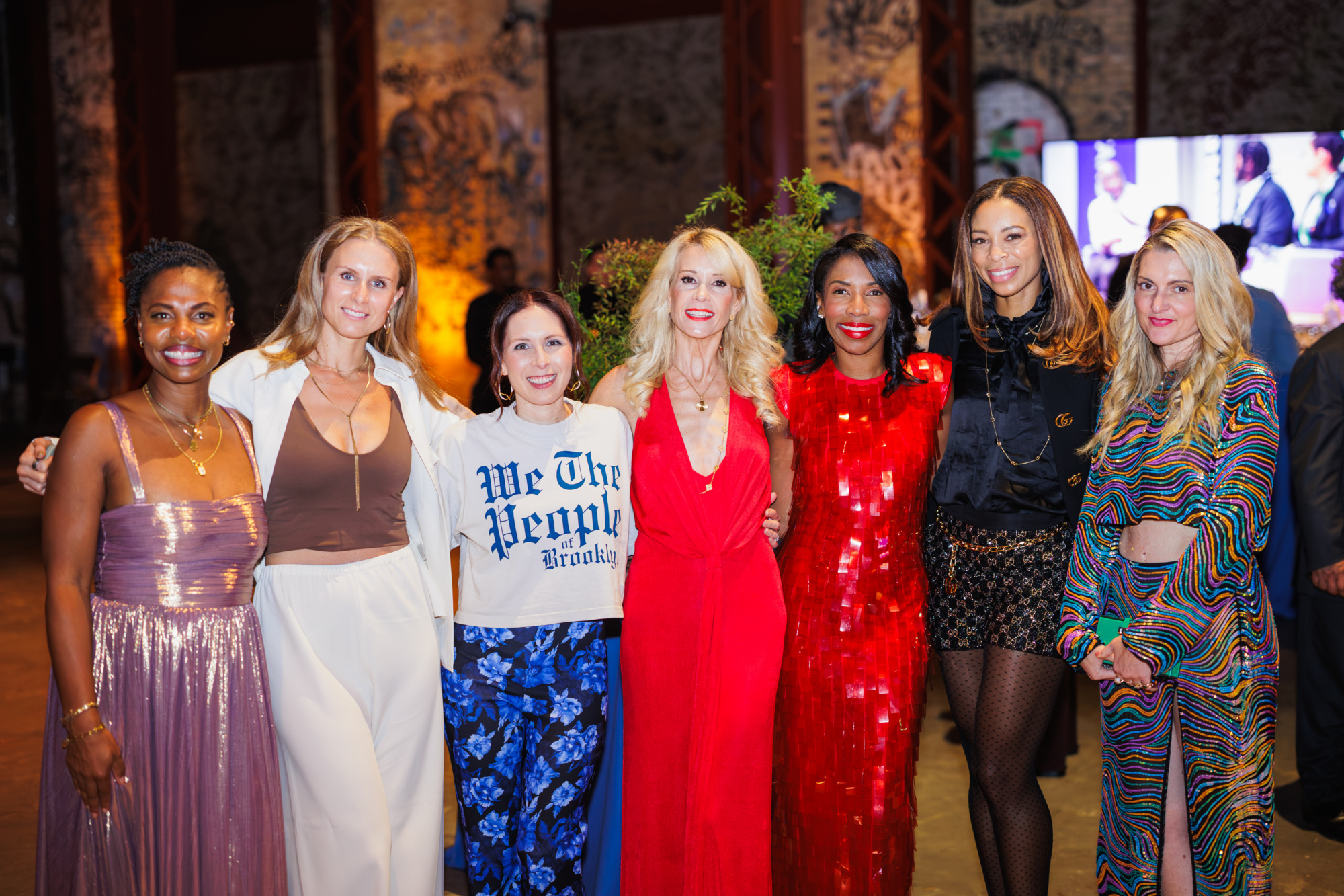 Seven women standing in a line, posing for a group photo at an event.