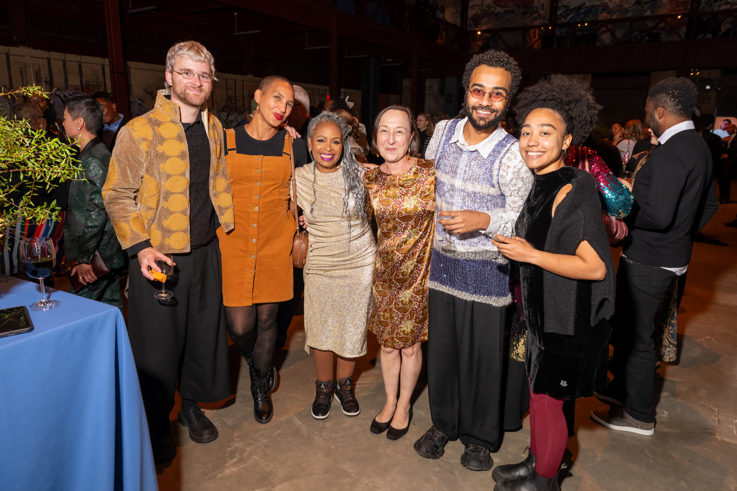 A group of six people posing together at an indoor event.